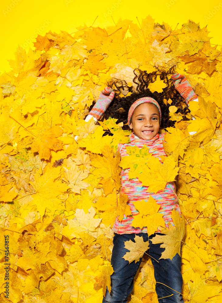Little African girl covered with autumn leaves Little African girl covered with autumn leaves