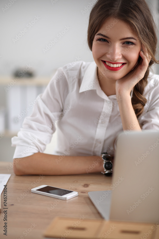Attractive businesswoman sitting on desk in the office Attractive businesswoman sitting on desk in the office