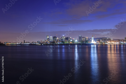Montreal over river panorama at dusk with city lights and urban buildings