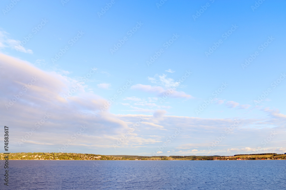 river and shore with settlements in distance on hot sunn