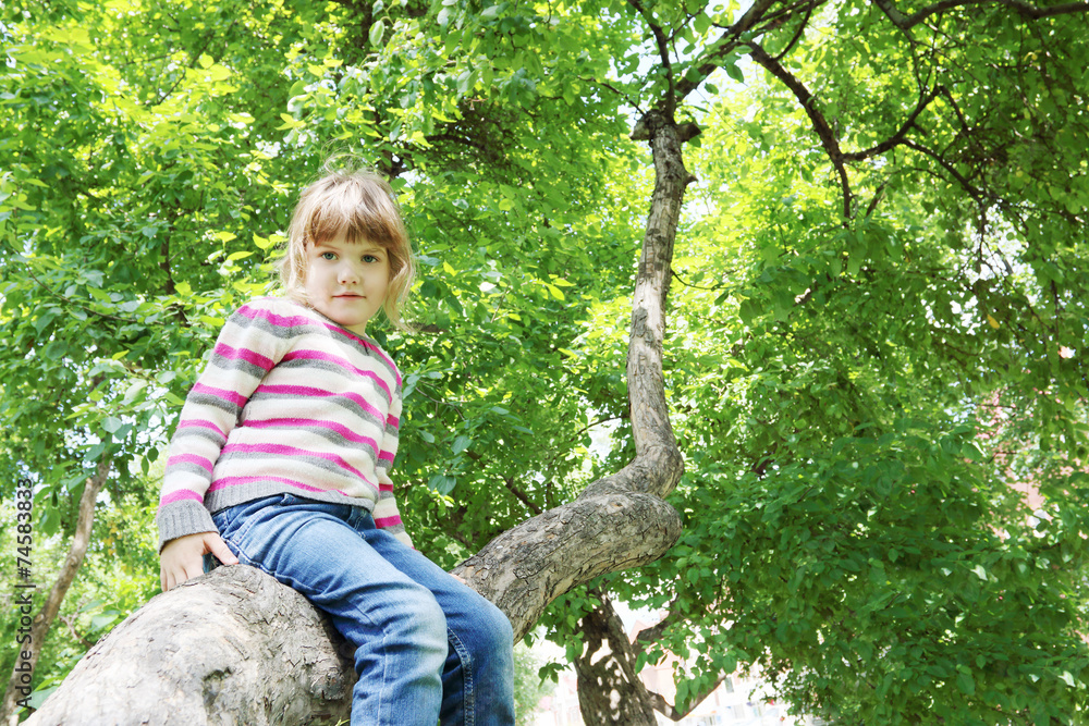 Girl in striped sweater sitting on tree trunk and looking Girl in striped sweater sitting on tree trunk and looking