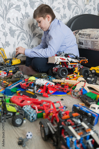 Teenage boy playing with toy cars in room