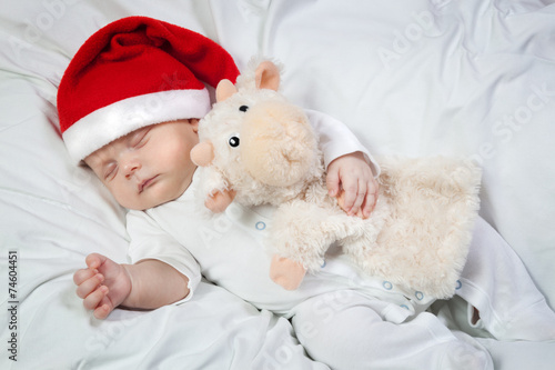 Baby in Christmas hat asleep hugging favorite toy