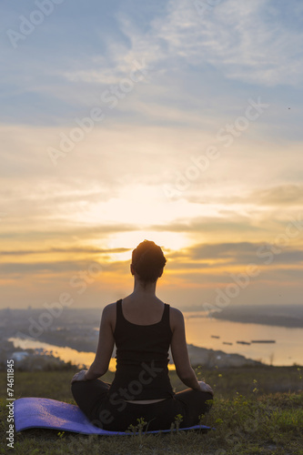 Young girl meditating and looking at sunset