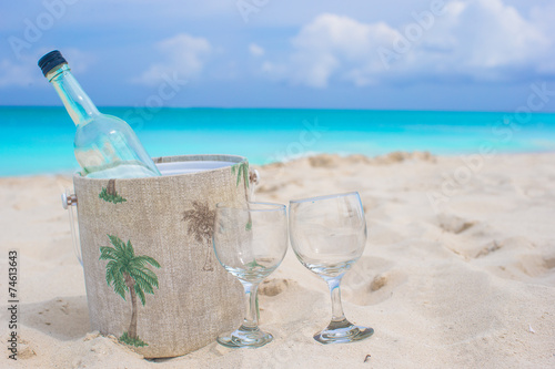 Bottle of wine and two glasses on sandy beach