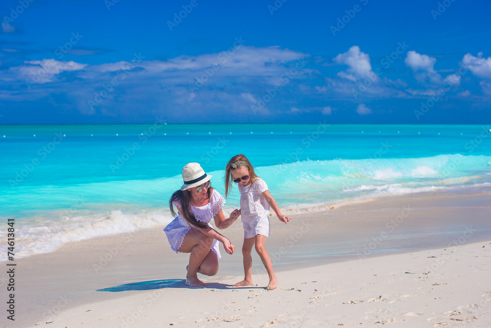 Happy mother and little daughter have fun during tropical beach
