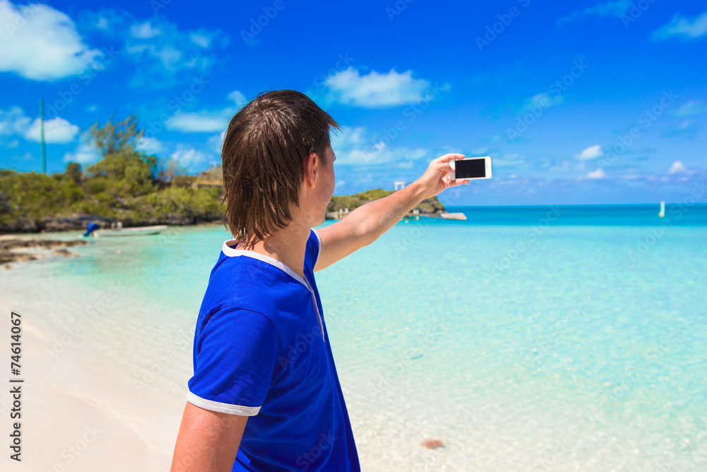 Young man with phone on tropical caribbean beach
