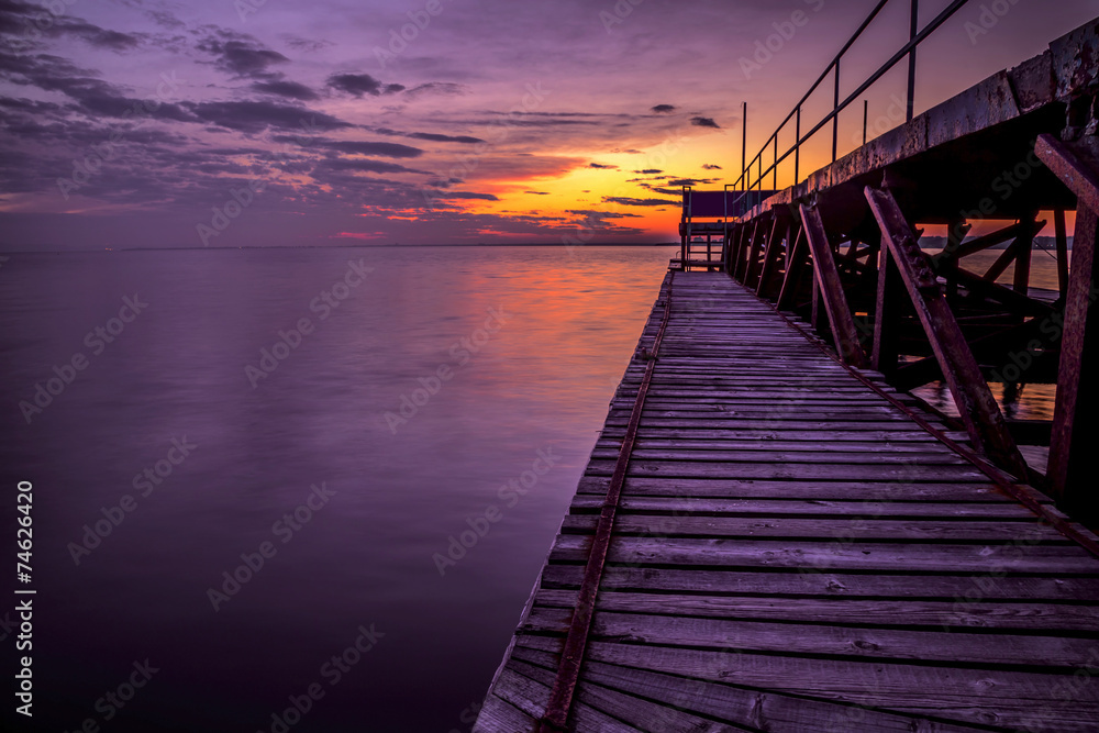 Fototapeta premium Pier in sea at sunset