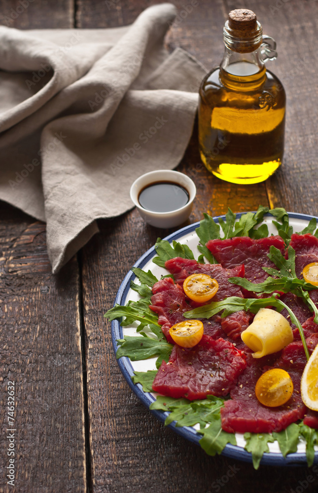 Carpaccio on the white plate on the wooden table Carpaccio on the white plate on the wooden table