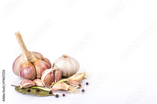 several garlic on a bay leaf and black pepper