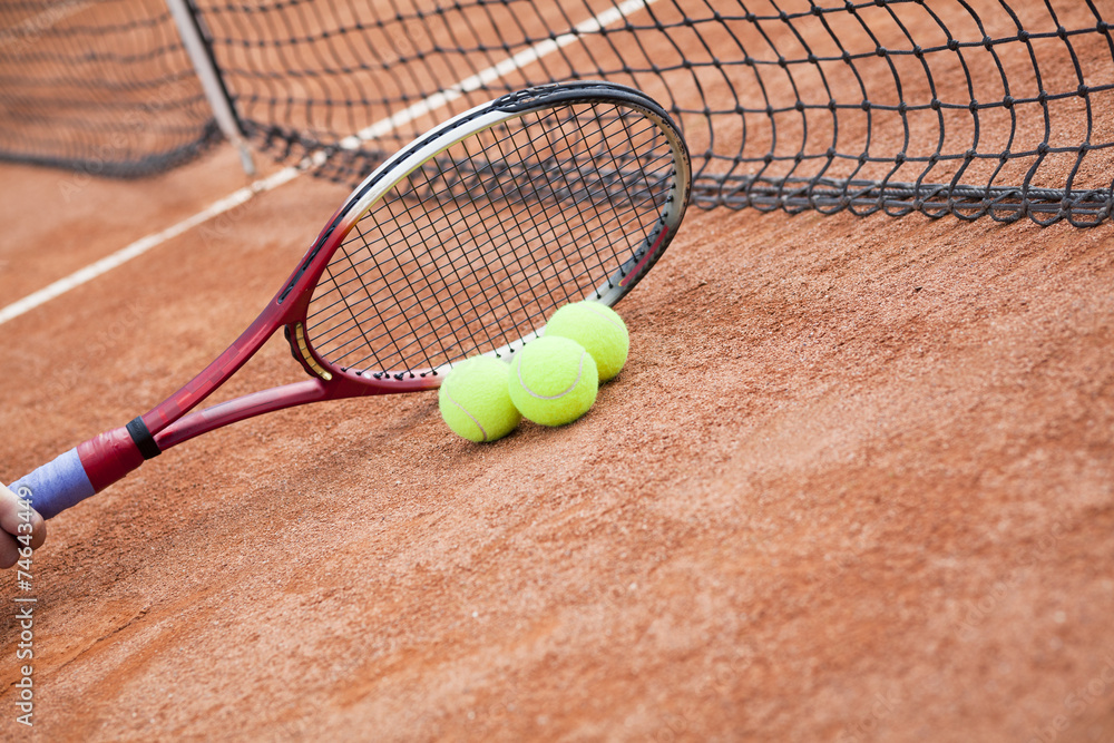 Close up of tennis racquet and balls on the clay tennis court 