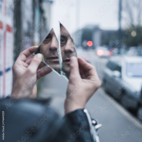 Punk guy looking at himself in a shattered mirror