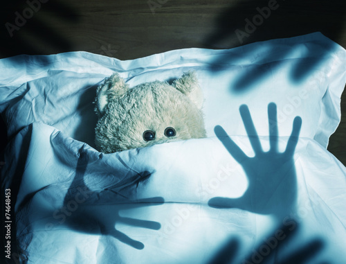 Adorable teddy bear laying in bed, scared