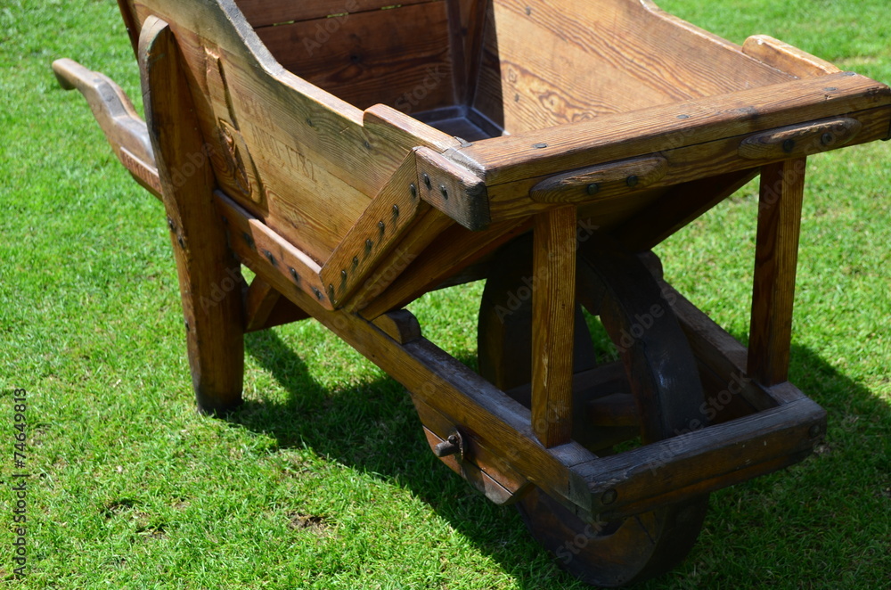 Handmade model of an wooden wheelbarrow standing in the garden