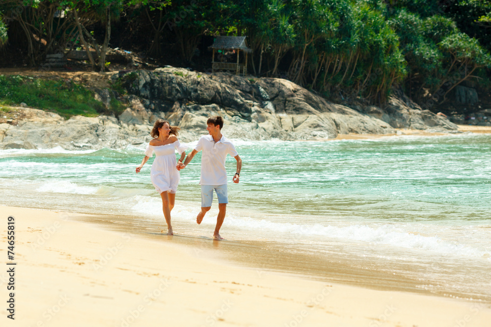 happy couple running on tropical beach