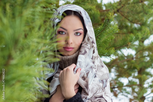 woman with a scarf  in the winter forest near fir trees snow