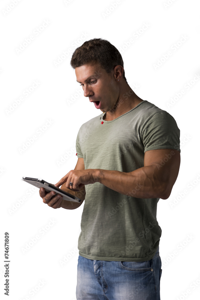 Muscular young man reading from e-book device with surprised Muscular young man reading from e-book device with surprised
