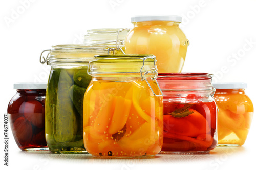 Jars with pickled vegetables and fruity compotes on white