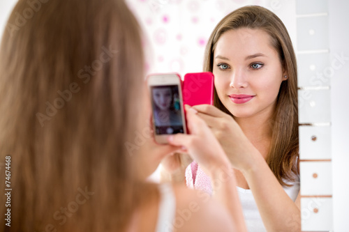 Beautiful teenager girl taking selfie in bathroom