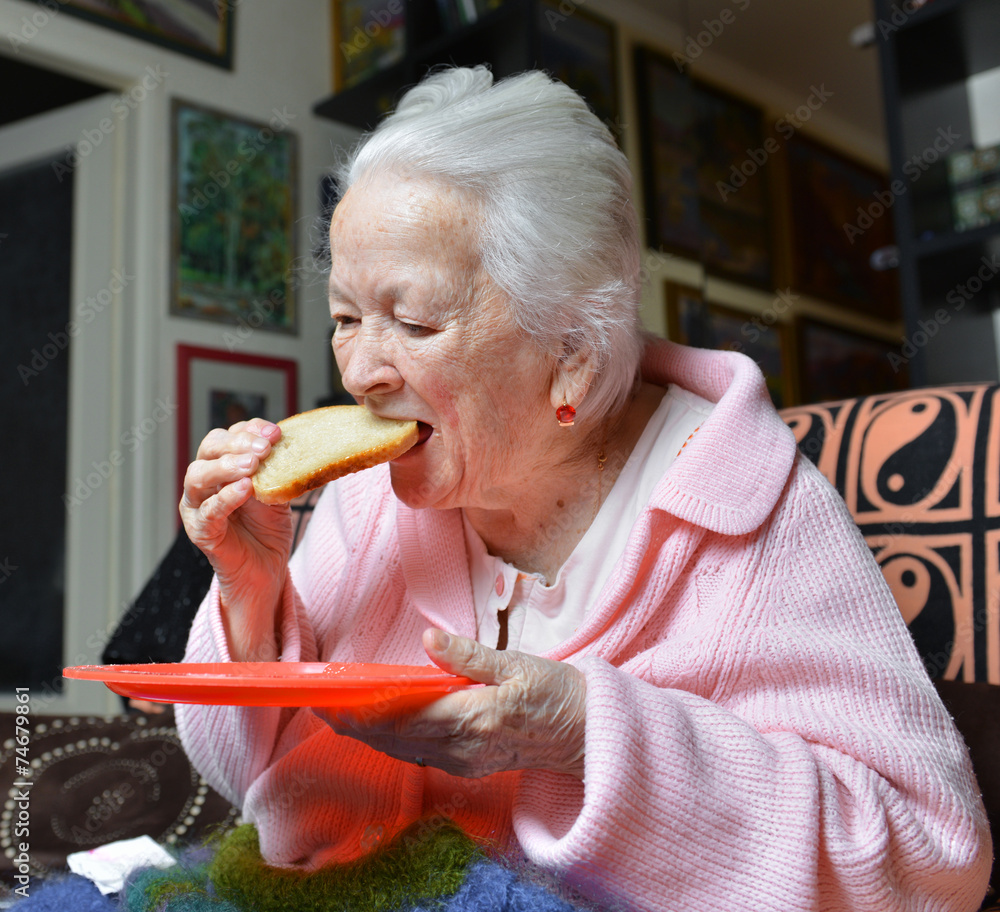Old woman eating a slice of bread