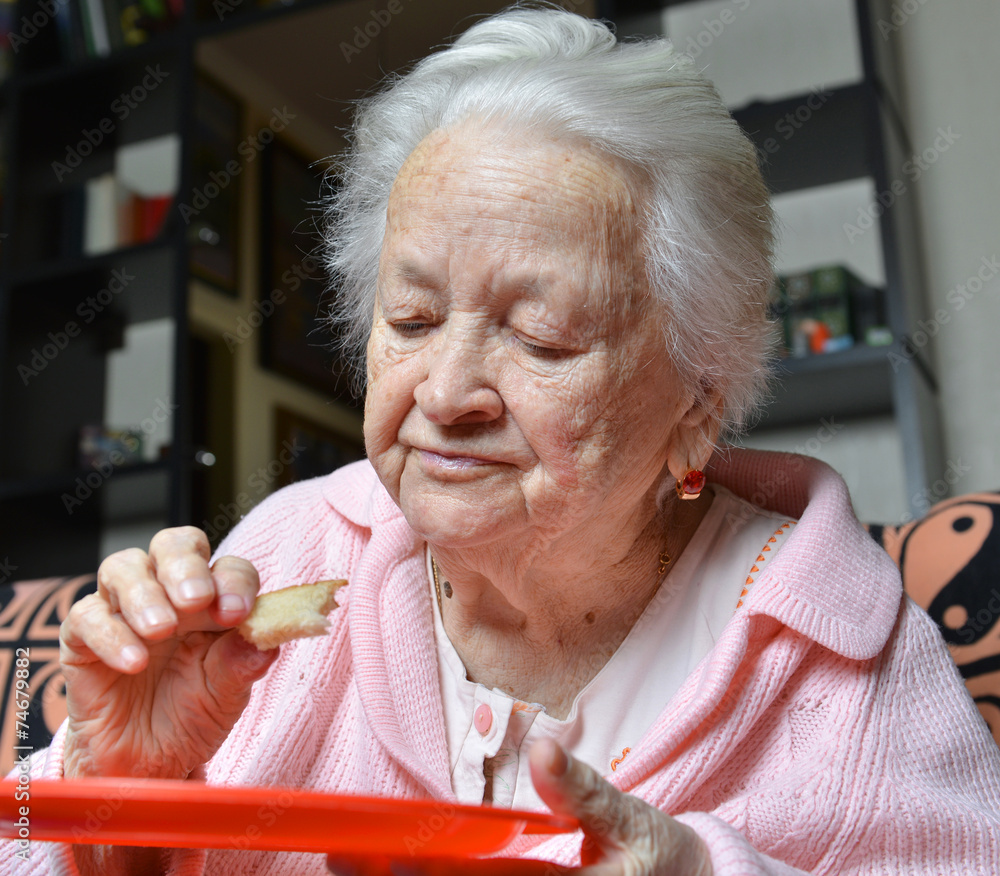 Old woman eating a slice of bread