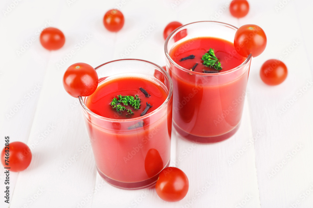 Tomato juice in glasses and fresh tomatoes on wooden background Tomato juice in glasses and fresh tomatoes on wooden background