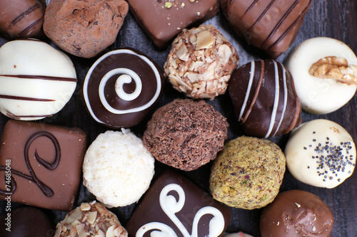 Assorted chocolates on the dark wooden smooth background