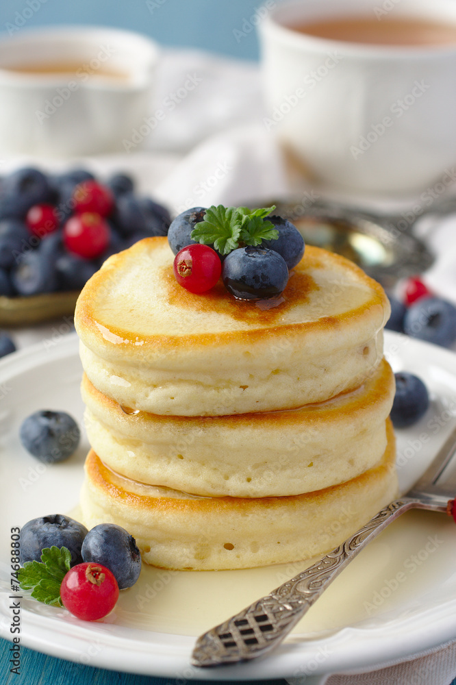 Stack of pancakes with fresh berries and honey
