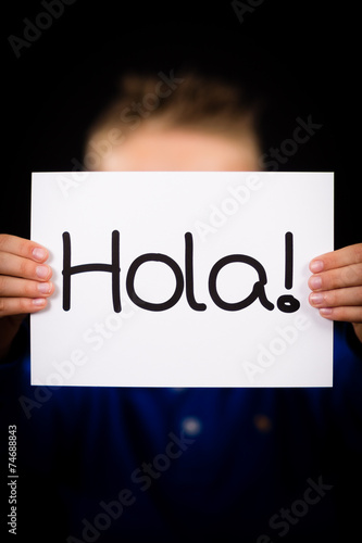 Child holding sign with Spanish word Hola - Hello