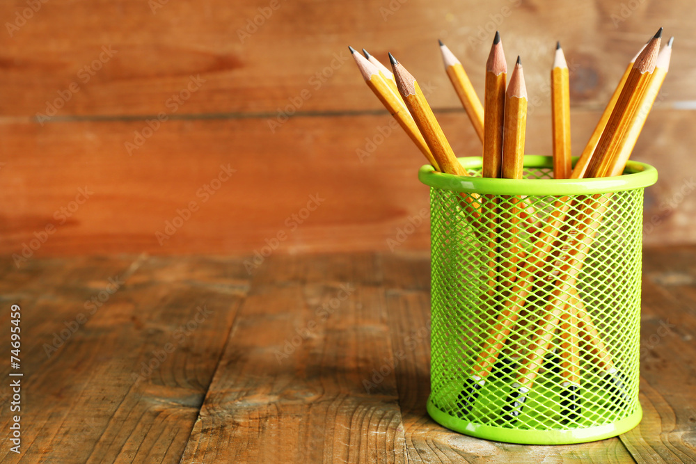 Pencils in metal holder on rustic wooden background