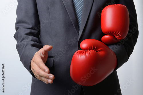 Businessman remove boxing gloves to offer a handshake on white b