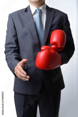 Businessman take off boxing gloves to offer a handshake on white © num_skyman