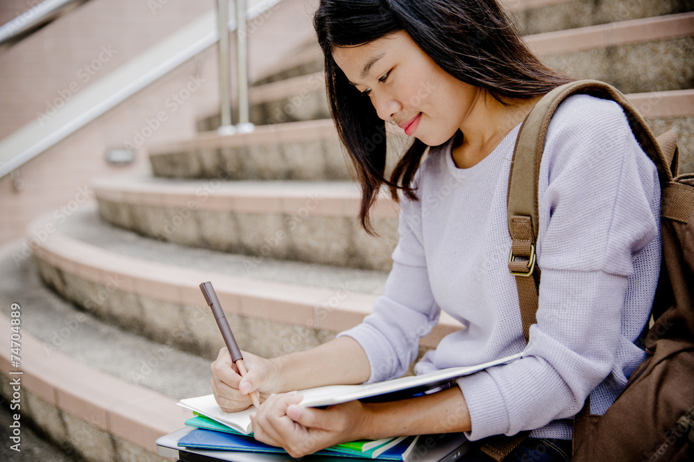 attractive female college student sitting on stairs