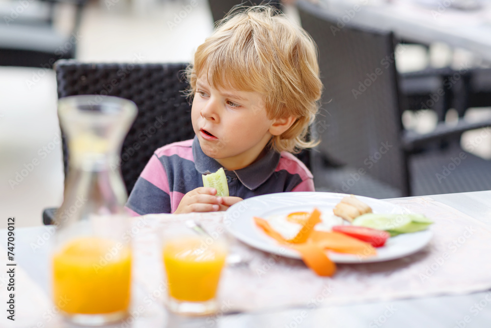Little kid boy having healthy breakfast in hotel restaurant or c Little kid boy having healthy breakfast in hotel restaurant or c