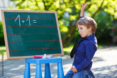 Little boy at blackboard practicing mathematics photo