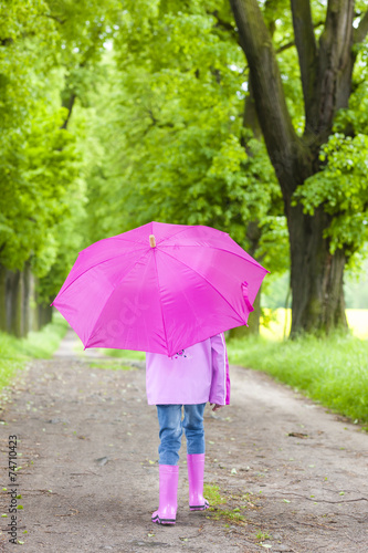 little girl wearing rubber boots with umbrella in spring alley © Richard Semik