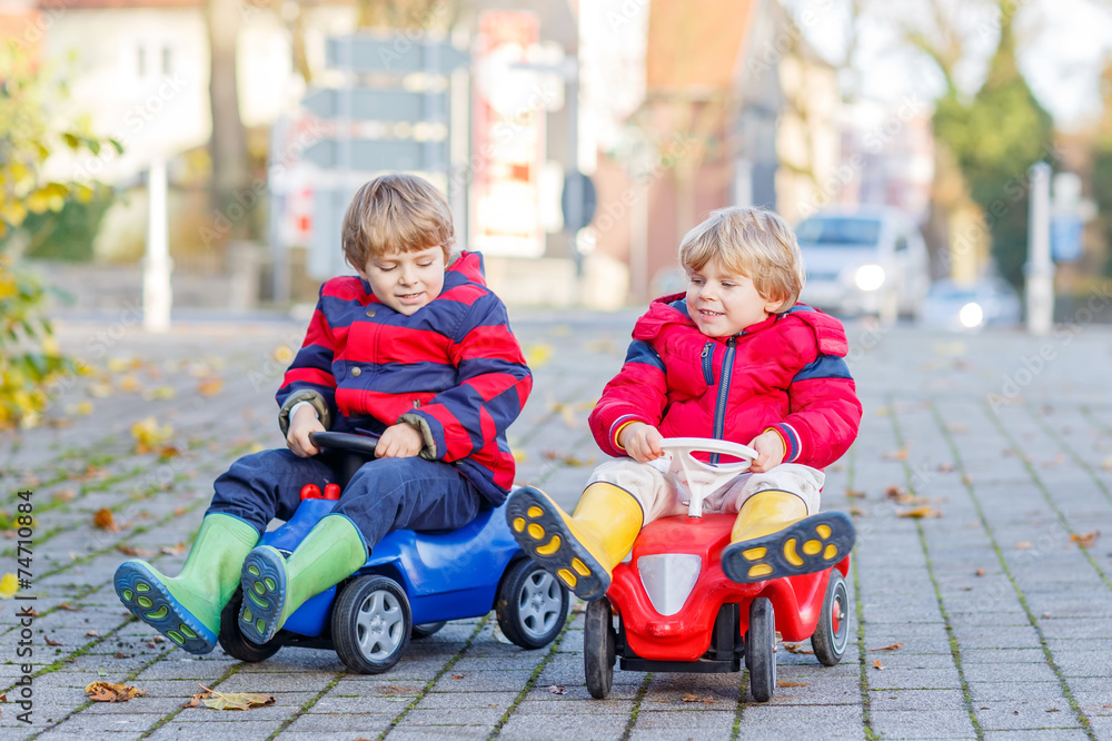 Two happy friends boys playing with colorful toy car, outdoors Two happy friends boys playing with colorful toy car, outdoors