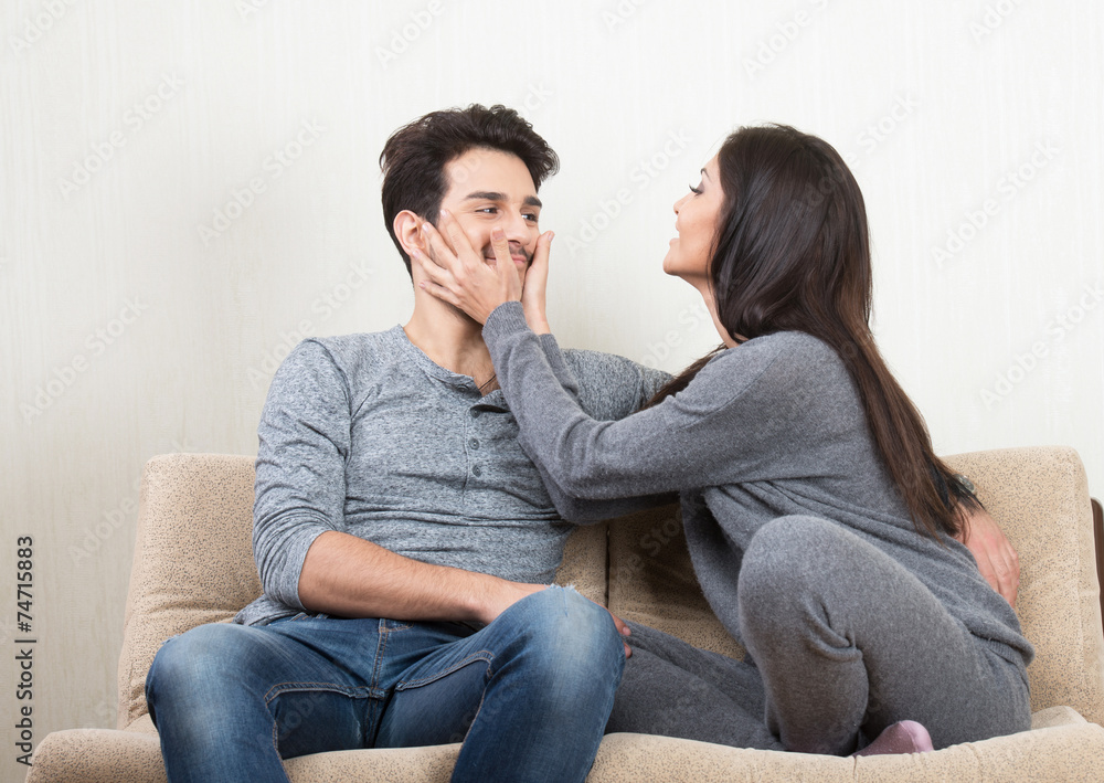 Young happy couple laughing together sitting on a sofa Young happy couple laughing together sitting on a sofa