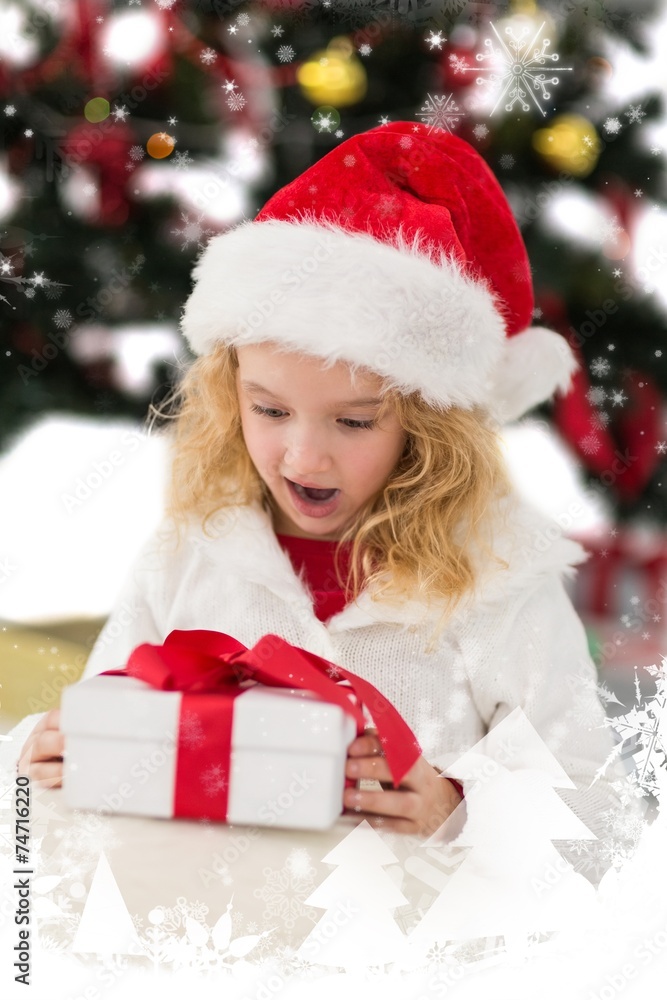 Composite image of festive little girl looking at gift Composite image of festive little girl looking at gift