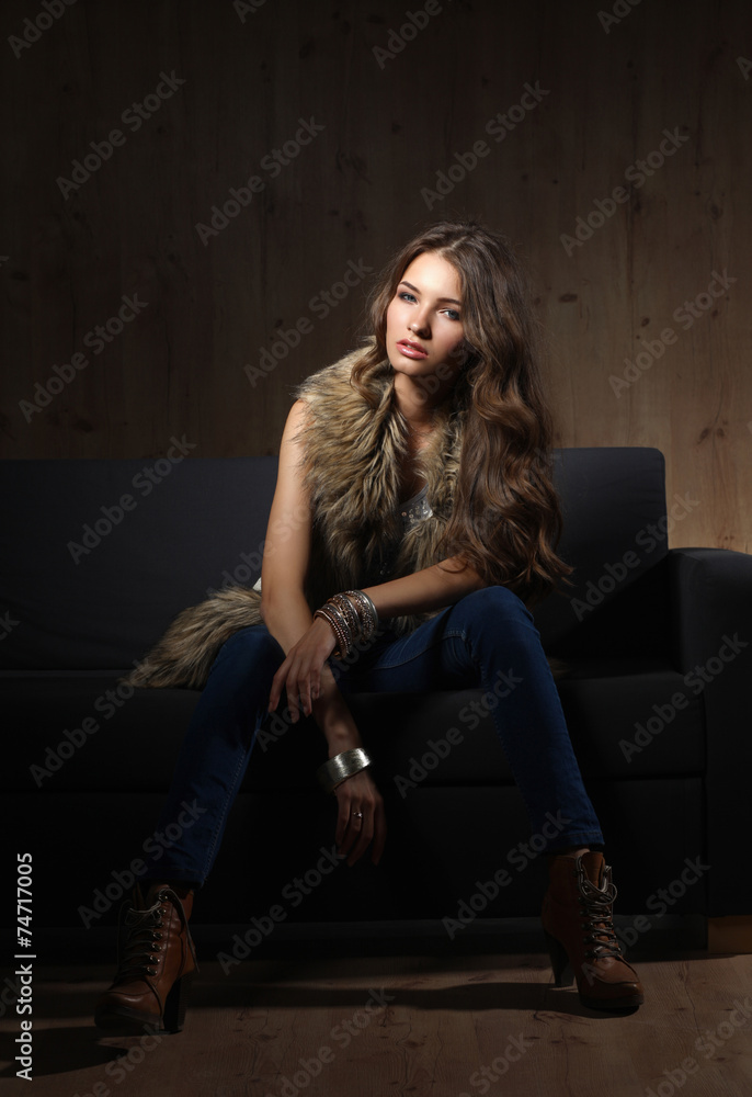 Portrait of elegant woman sitting on black sofa wearing a blue Portrait of elegant woman sitting on black sofa wearing a blue