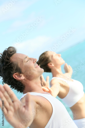 Couple doing yoga and relaxation exercises by the sea