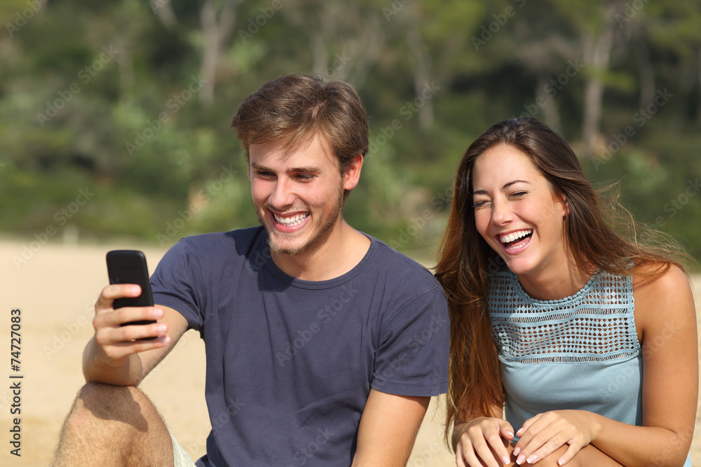 Funny man and woman laughing watching the smart phone Funny man and woman laughing watching the smart phone