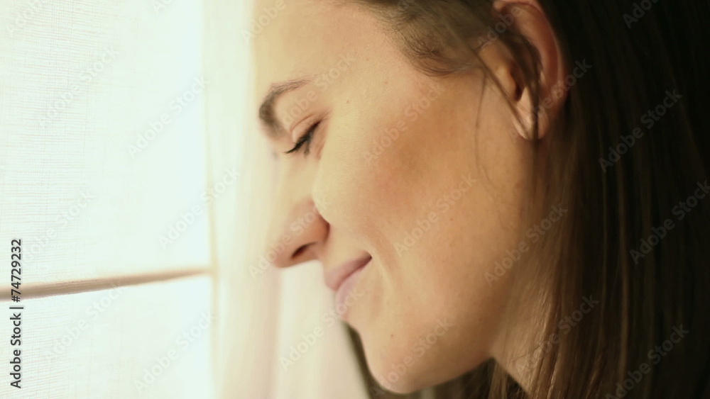 Portrait of a beautiful smiling brunette at the window, close up Portrait of a beautiful smiling brunette at the window, close up