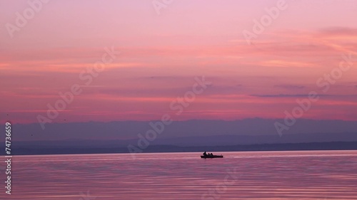 children on a boat on a lake sunset have fun in silhouette