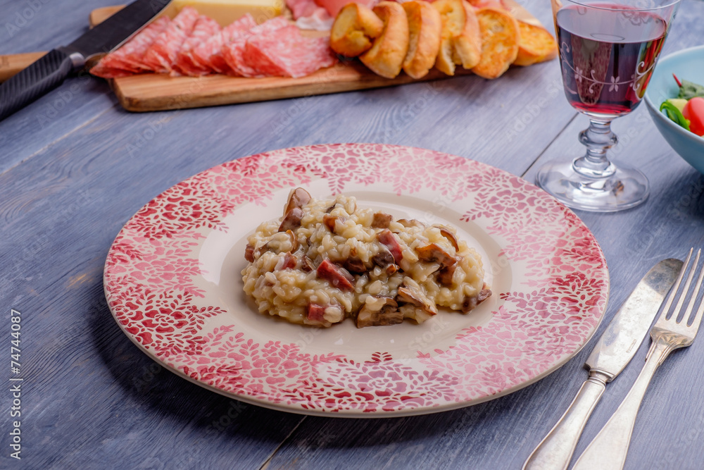 Risotto on a wood table with some antipasto in the background Risotto on a wood table with some antipasto in the background