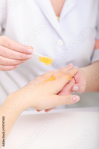 Beautician applying moisturizing cream on client hands.