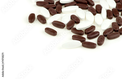 Brown and white pill tablets scattered on isolated white backgro