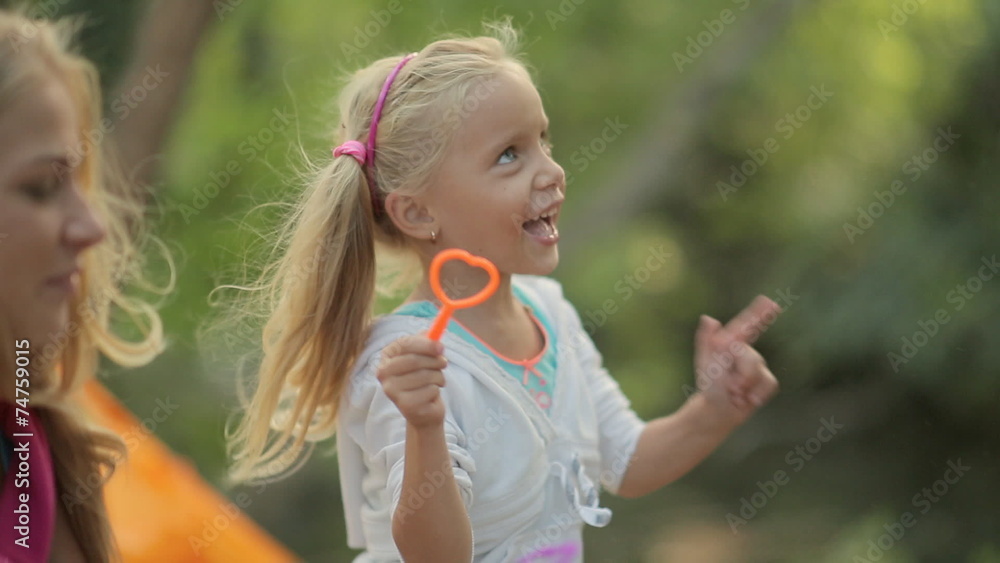 Little girl with her family blowing soap bubbles and laughing Little girl with her family blowing soap bubbles and laughing