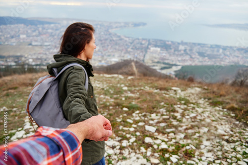 Woman holding man's hand and leading him on nature