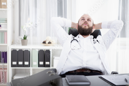 Arzt sitzt am Schreibtisch in seiner Praxis und gr  belt